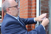 Bild vergr&ouml;&szlig;ern: Landrat Thorsten Kr&uuml;ger klebt den Aufkleber an die Eingangst&uuml;r des Kreishauses